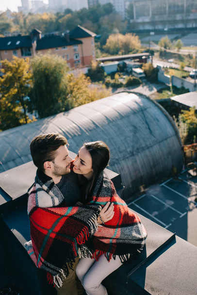 high angle view of happy young couple covered in plaid kissing on rooftop - Foto, afbeelding