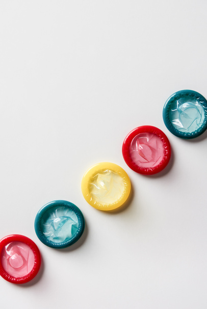 top view of multicolored condoms on white background - Foto, afbeelding