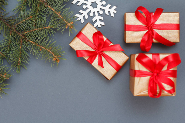 クリスマス装飾。ギフト用の箱、灰色の背景に装飾的な snowflacke とモミの木の枝します。平面図です。クリスマスのグリーティング カードの概念. - 写真・画像