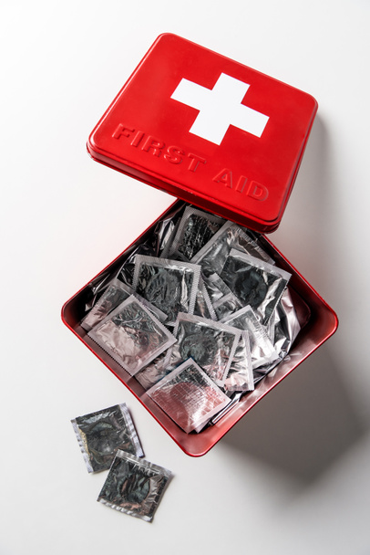 vista superior del botiquín de primeros auxilios caja roja con condones plateados aislados en blanco
  - Foto, Imagen