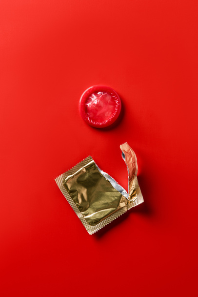 top view of red condom and golden packaging on red background - Photo, Image