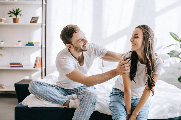 laughing young couple having fun while sitting on bed in morning - Fotoğraf, Görsel