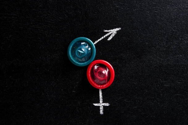 ylhäältä näkymä kondomeja miesten ja naisten merkkejä mustalla taustalla
 - Valokuva, kuva