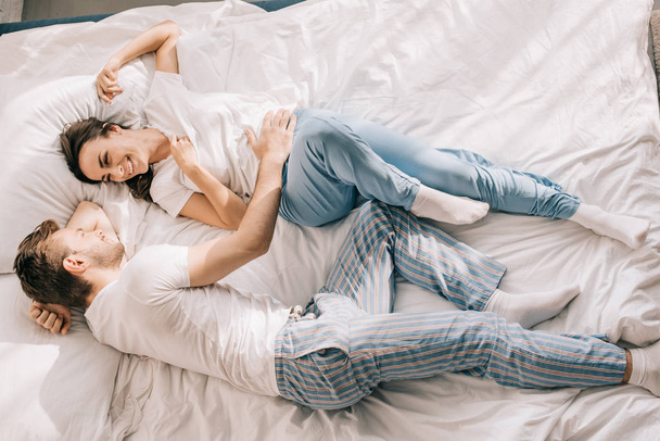 top view of beautiful young couple having fun in bed in morning - Photo, Image