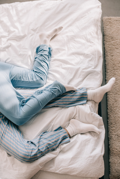 朝のベッドでリラックスしたパジャマ姿でカップルのクロップ撮影 - 写真・画像
