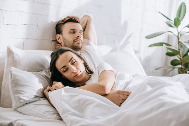 attractive young couple sleeping in bed in morning - Фото, изображение