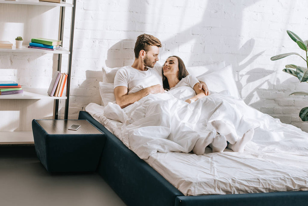 beautiful young couple relaxing and chatting in bed in morning - Φωτογραφία, εικόνα