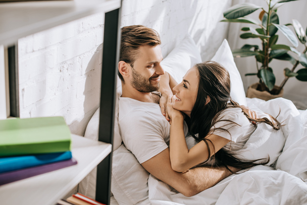 happy young couple relaxing and chatting in bed in morning - Photo, Image
