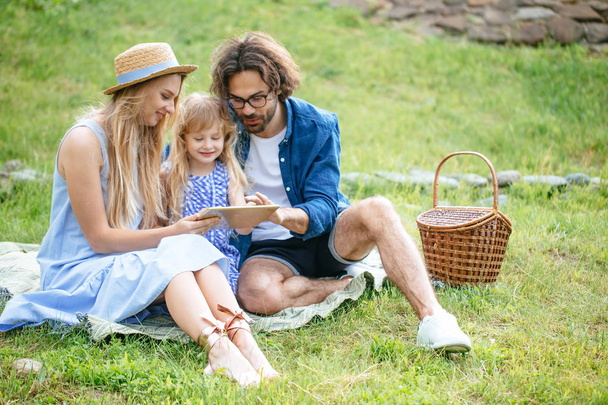 family using digital tablet during picnic at countryside - Foto, afbeelding