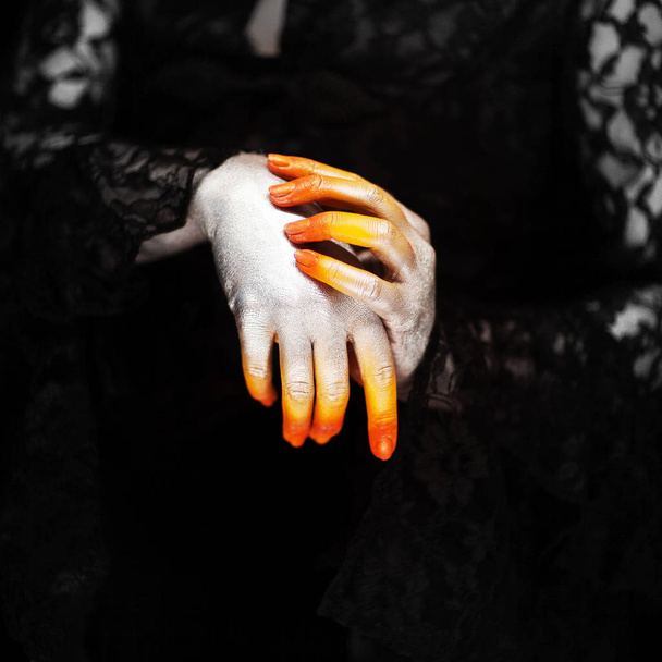 Creepy halloween vampire hands close up in red orange and silver on black, can be used as background - Photo, image