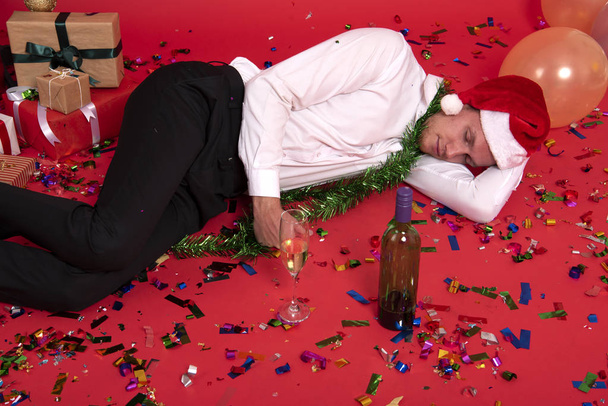 Young businessman hangover sleeping after drinking of alcohol in office. christmas and happy new year party. - 写真・画像