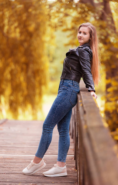 Beautiful woman on the wooden bridge an autumn day - Фото, зображення