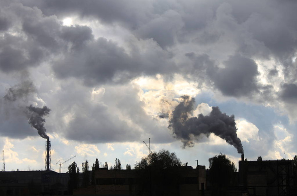 Teollisuuden tehdas saastuttaa ilmakehän ja ekologian haitallisia kemikaalien käsittelyn päästöjä sinistä pilvistä dramaattista taivasta vastaan
 - Valokuva, kuva