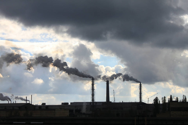 Industriële fabriek vervuilt sfeer en ecologie schadelijke emissies van chemische verwerking tegen de blauwe bewolkt dramatische hemel - Foto, afbeelding