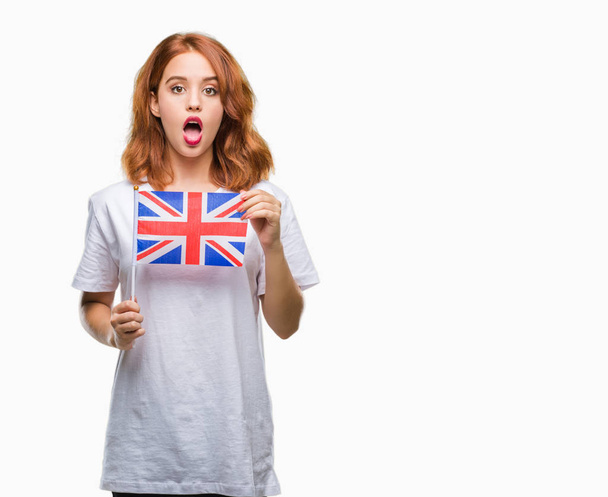 Mladá krásná žena držící vlajka Spojeného království izolované pozadí strach v šoku s tváří překvapení, strach a vzrušený výraz strachu - Fotografie, Obrázek