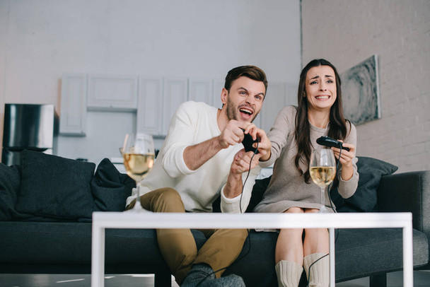 jeune couple expressif jouant jeu vidéo rétro sur le canapé à la maison
 - Photo, image