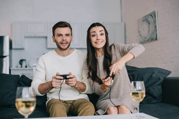 happy young couple playing retro video game on couch at home - Fotografie, Obrázek