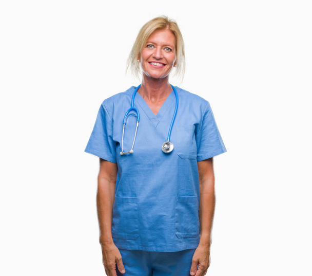 Średnim wieku kobieta lekarz chirurg Blondynka pielęgniarka na białym tle z poważną miną na twarzy. Proste i naturalne, patrząc na kamery. - Zdjęcie, obraz