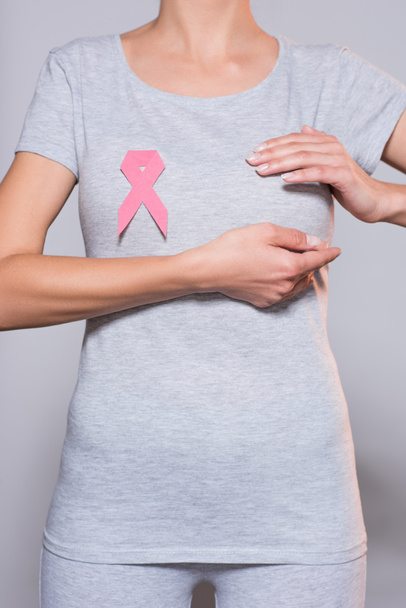 cropped shot of woman with breast cancer awareness pink ribbon on grey background - Photo, Image