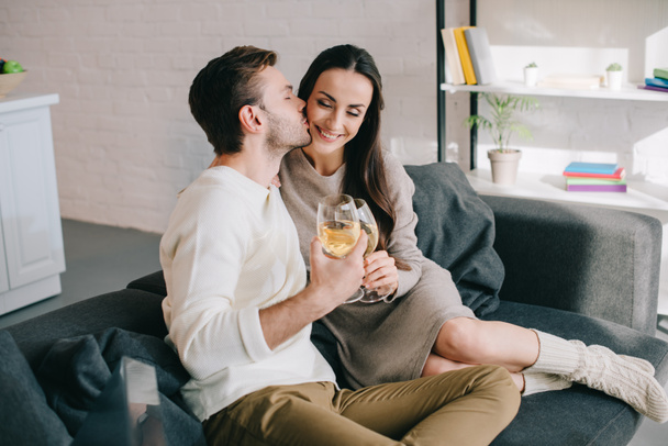 beautiful young couple drinking wine and flirting on couch at home - Φωτογραφία, εικόνα