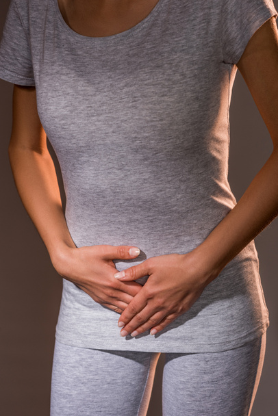 oříznutý snímek žena pocit nepohodlí v ženské reprodukční systém na tmavém pozadí - Fotografie, Obrázek