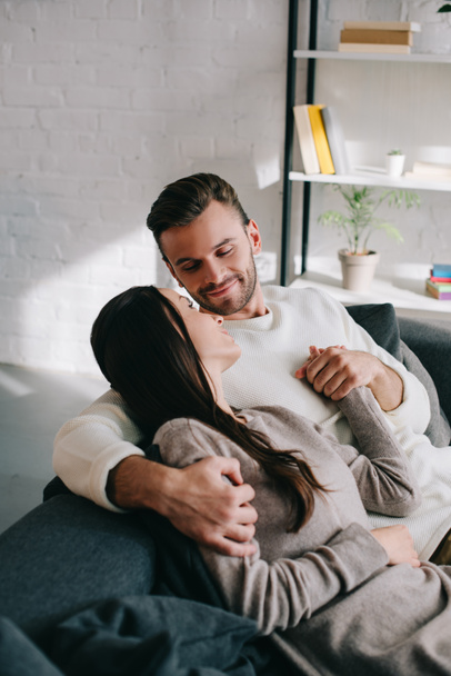 beautiful young couple relaxing on couch and holding hands at home - Zdjęcie, obraz