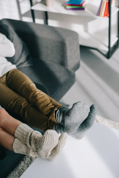 обрізаний знімок пари у вовняних шкарпетках, що розслабляються на дивані вдома
 - Фото, зображення