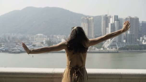 Young woman stretching arms and admire cityscape standing on terrace in city - Filmati, video