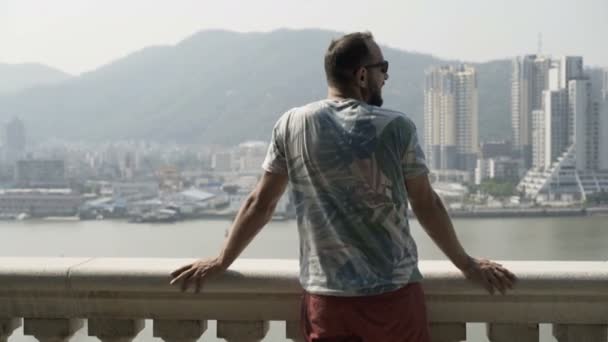 junger Mann bewundert Stadtbild, das auf einer Terrasse in der Stadt steht - Filmmaterial, Video