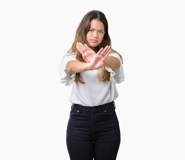 Young beautiful brunette business woman over isolated background Rejection expression crossing arms and palms doing negative sign, angry face - Foto, Bild
