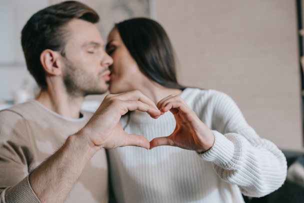 beautiful young couple kissing and making heart symbol with hands - Foto, imagen
