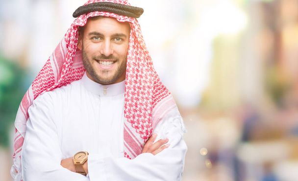 Jovem homem bonito vestindo keffiyeh sobre fundo isolado rosto feliz sorrindo com os braços cruzados olhando para a câmera. Pessoa positiva
. - Foto, Imagem