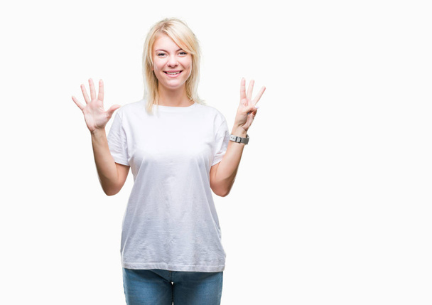 Giovane bella donna bionda che indossa t-shirt bianca su sfondo isolato mostrando e indicando con le dita il numero otto sorridendo fiducioso e felice
. - Foto, immagini
