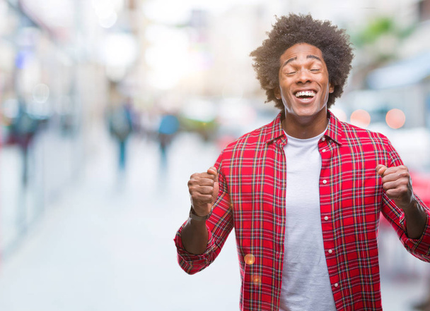 Hombre afroamericano sobre fondo aislado emocionado por el éxito con los brazos levantados celebrando la victoria sonriendo. Concepto ganador
. - Foto, imagen