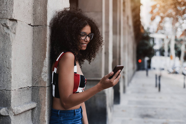 Portrait of a dazzling caucasian girl leaning against the wall and having a video call with her friend via the smartphone, with a copy space place on the right for advertising message or your logo - Foto, Bild