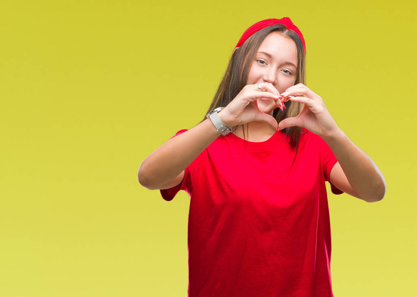 Jonge Kaukasische mooie vrouw over geïsoleerde achtergrond glimlachend in liefde met hartsymbool en vorm met de handen. Romantische concept. - Foto, afbeelding