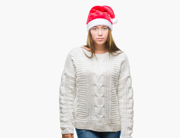 Молодая красивая белая женщина в рождественской шляпе на изолированном фоне с серьезным выражением лица. Простой и естественный взгляд на камеру
. - Фото, изображение