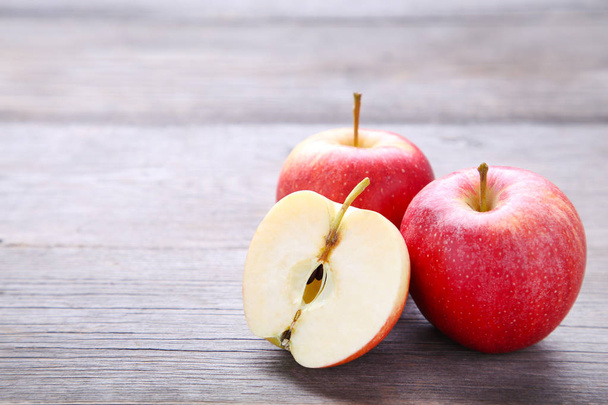 Ripe red apples on a grey wooden background. Half of apple - Φωτογραφία, εικόνα