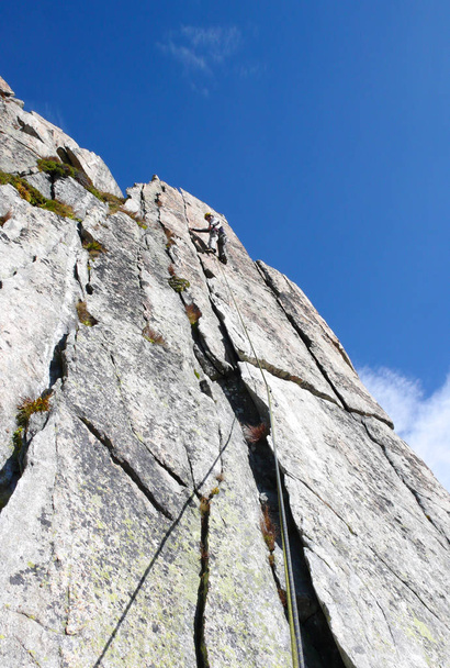 guide rock bergbeklimmer op een steile granieten route in de Alpen van Zwitserland op een mooie dag - Foto, afbeelding