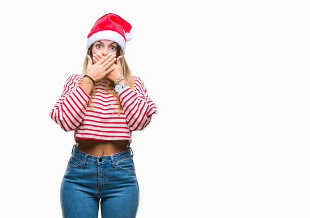 Młoda piękna kobieta sobie Boże Narodzenie kapelusz na białym tle szoku, obejmujące usta rękami za błąd. Koncepcja tajne. - Zdjęcie, obraz