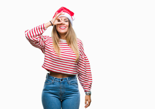 若くてきれいな女性手の笑顔、幸せそうな顔で指を通して見る目で ok のジェスチャーを行う分離の背景にクリスマスの帽子をかぶって. - 写真・画像