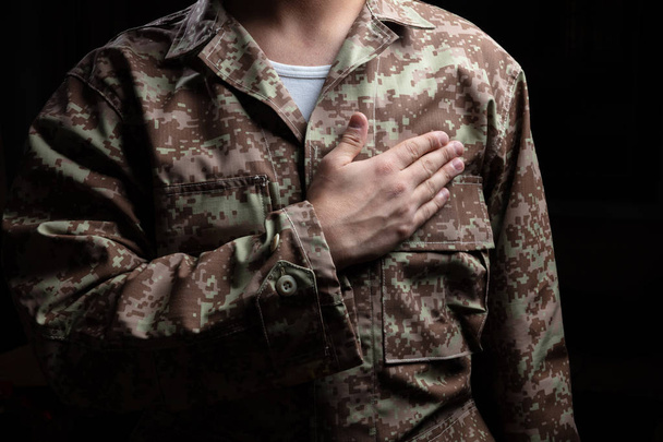 US Army. Young soldier with hand on heart standing on black background - Zdjęcie, obraz