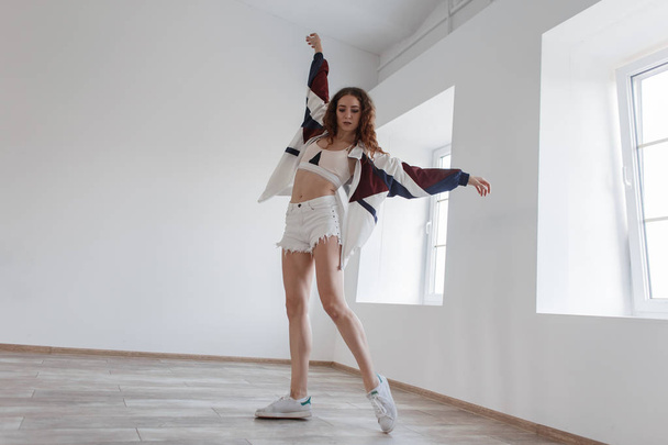 Young beautiful girl in fashionable sportswear and shorts dancing in a dance class - Photo, Image