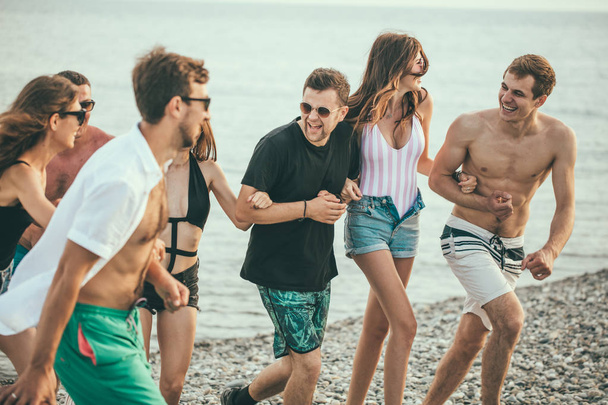Group of Friends Walking at Beach, having fun, womans piggyback on mans, funny vacation - Foto, afbeelding