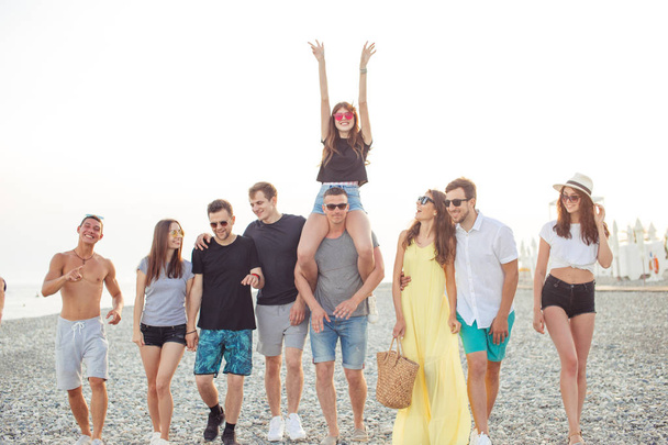 Група друзів, які ходять на пляжі, розважаються, жінка - голуб'ятник чоловікам, смішна відпустка. - Фото, зображення
