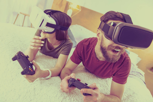 Smiling boyfriend and girlfriend testing virtual reality glasses - Fotó, kép