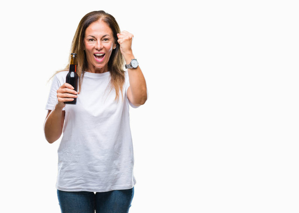 Mujer hispana de mediana edad bebiendo cerveza sobre un fondo aislado molesta y frustrada gritando con ira, loca y gritando con la mano levantada, concepto de ira
 - Foto, Imagen