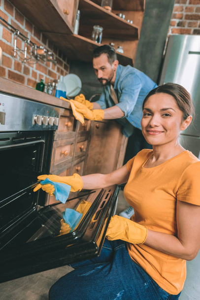 Cheerful female person cleaning her kitchen - Photo, Image