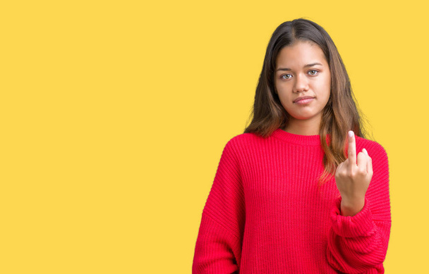junge schöne brünette Frau trägt roten Winterpullover über isoliertem Hintergrund zeigt Mittelfinger, unhöflich und unhöflich fuck off Ausdruck - Foto, Bild