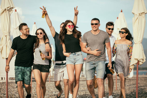 holidays, vacation. group of friends having fun on beach, walking, drink beer, smiling and hugging - Fotoğraf, Görsel